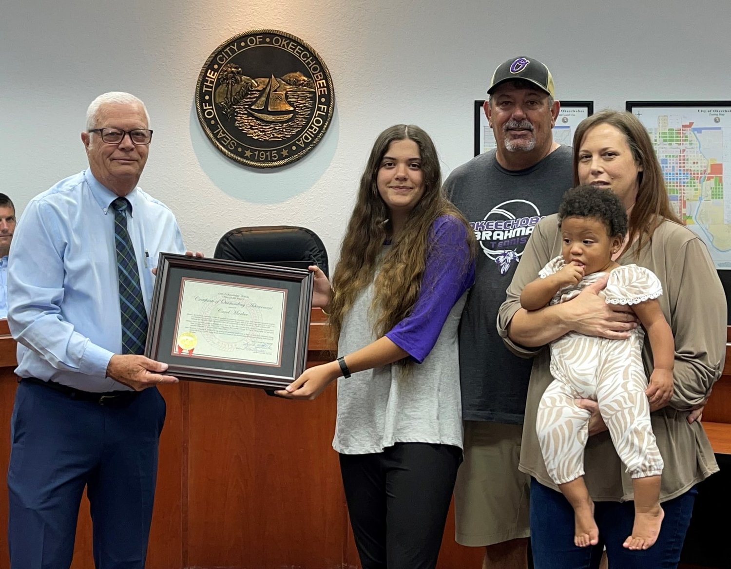 Mayor Dowling Watford (left) presents a certificate of appreciation to Carol Marker (center) as her family looks on proudly.